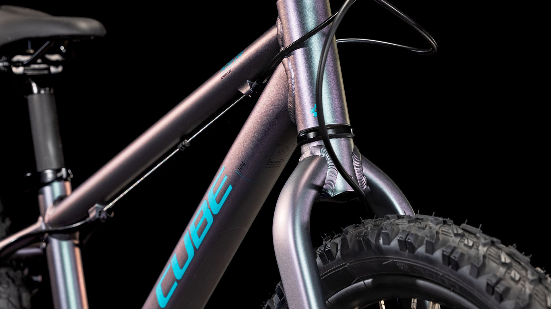 Nahaufnahme des CUBE Acid 200 Disc galactic´n´cyan 2025 Rahmens in Metallic-Optik mit blauem CUBE-Branding, Vorderreifen, Gabel und Kabeln auf schwarzem Hintergrund. Ausgestattet mit Shimano 7-Gang-Schaltung für moderne Performance.