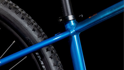Nahaufnahme des CUBE Acid 260 Disc actionteam 2025 von CUBE, die den blauen 6061-Aluminiumrahmen, das Hinterrad mit dickem Noppenreifen, das Sattelrohr und die Sattelstützenklemme vor einem schwarzen Hintergrund zeigt.