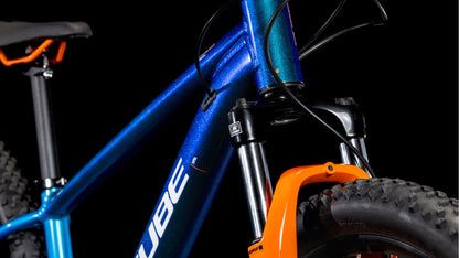 Nahaufnahme des CUBE Acid 260 Disc actionteam 2025 Mountainbike-Rahmens in Blau und Orange, hergestellt aus 6061er Aluminium, mit einem Teil der vorderen Federgabel, dicken Reifen und dem markanten CUBE-Logo auf schwarzem Hintergrund.