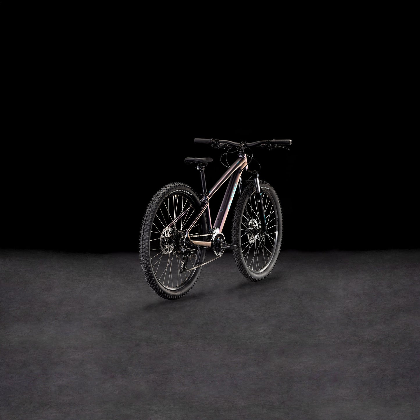 Das CUBE Acid 260 Disc galactic'n'cyan 2025 Mountainbike mit dicken Reifen, einem schlanken Rahmen aus Aluminiumrohrsatz und Shimano Schaltung ist vor einem dunklen Hintergrund mit Farbverlauf abgebildet, der nach links geneigt ist, um sowohl die Räder als auch den Lenker zu zeigen.