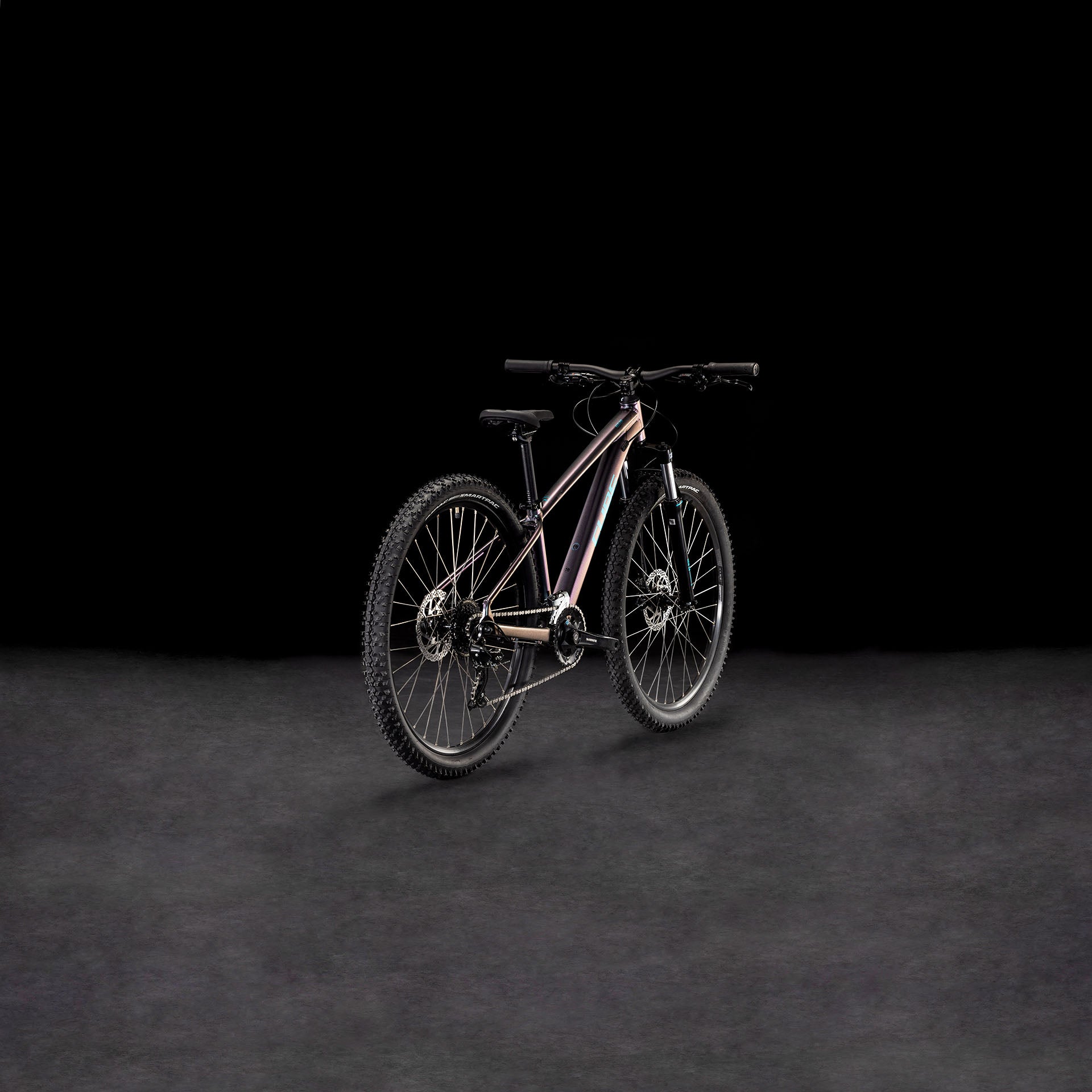 Das CUBE Acid 260 Disc galactic'n'cyan 2025 Mountainbike mit dicken Reifen, einem schlanken Rahmen aus Aluminiumrohrsatz und Shimano Schaltung ist vor einem dunklen Hintergrund mit Farbverlauf abgebildet, der nach links geneigt ist, um sowohl die Räder als auch den Lenker zu zeigen.
