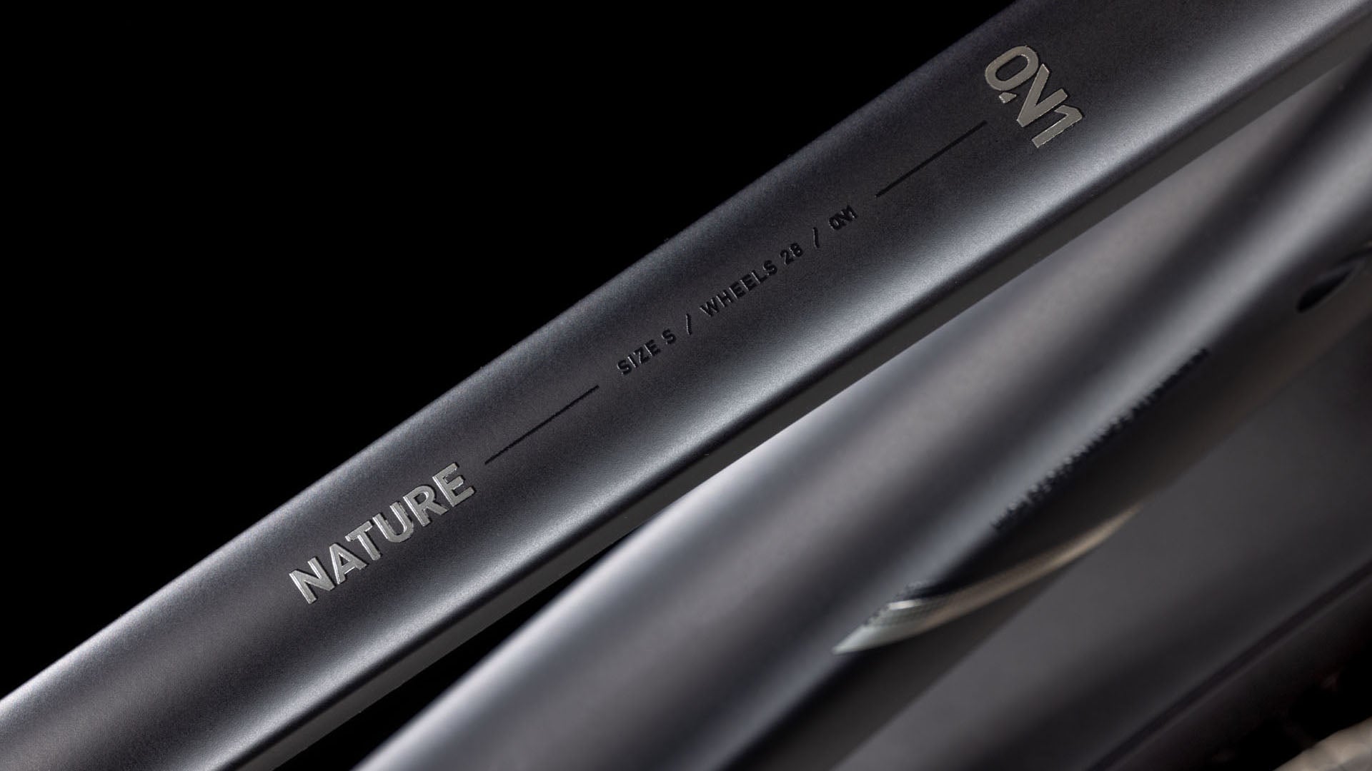 Nahaufnahme eines mattschwarzen CUBE Nature ONE Allroad black'n'black Rahmens mit NATURE, SIZE S, WHEELS 29 und ON1 in weiß auf dem Oberrohr, mit Shimano 1x8-Gang Schaltung, vor einem schwarzen Hintergrund.