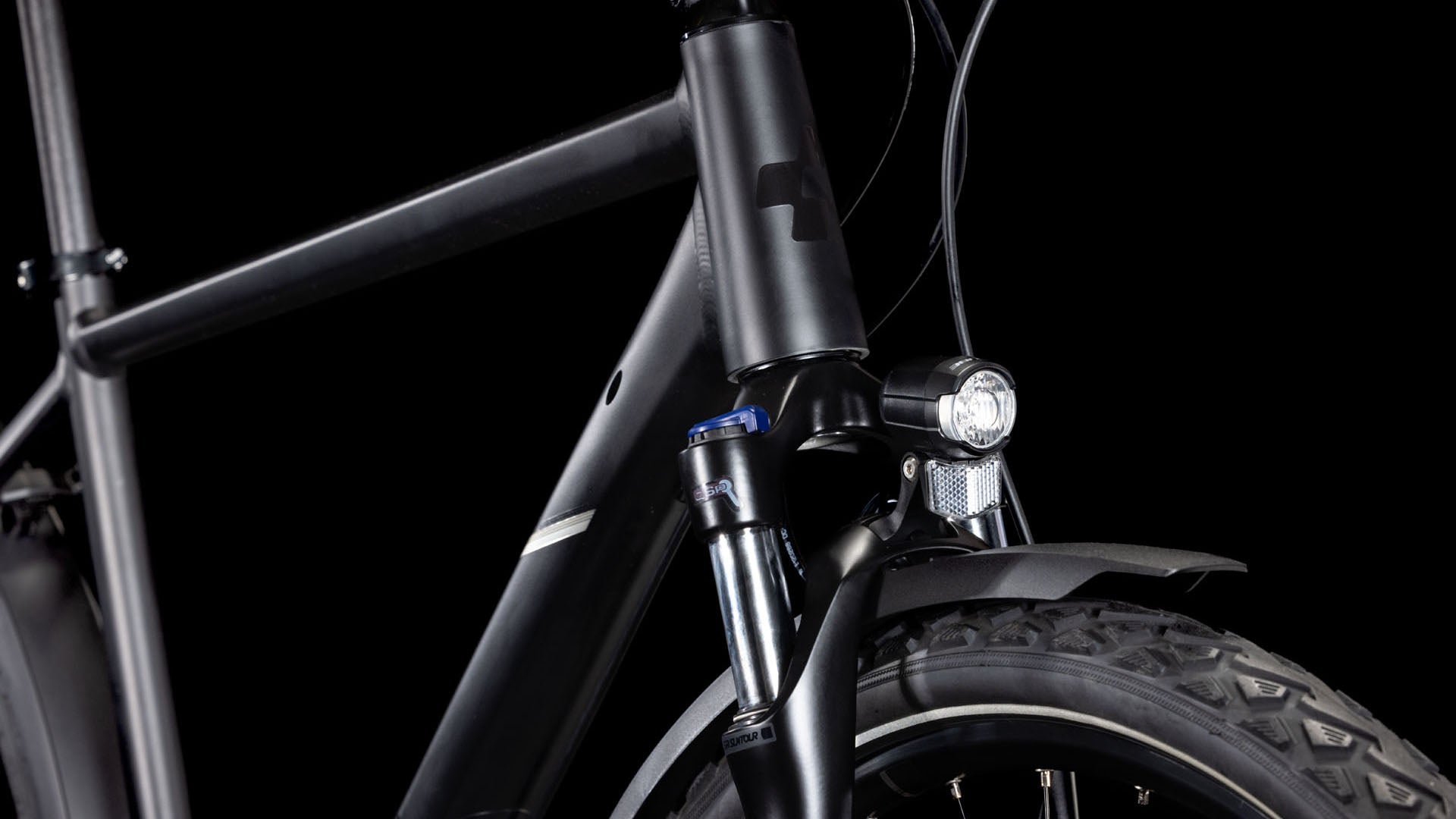 Nahaufnahme der Front des CUBE Nature ONE Allroad black'n'black, die Rahmen, Federgabel, Reifen, Vorderlicht und Schutzblech vor schwarzem Hintergrund hervorhebt. Verfügt über hydraulische Scheibenbremsen für überlegene Bremskraft.