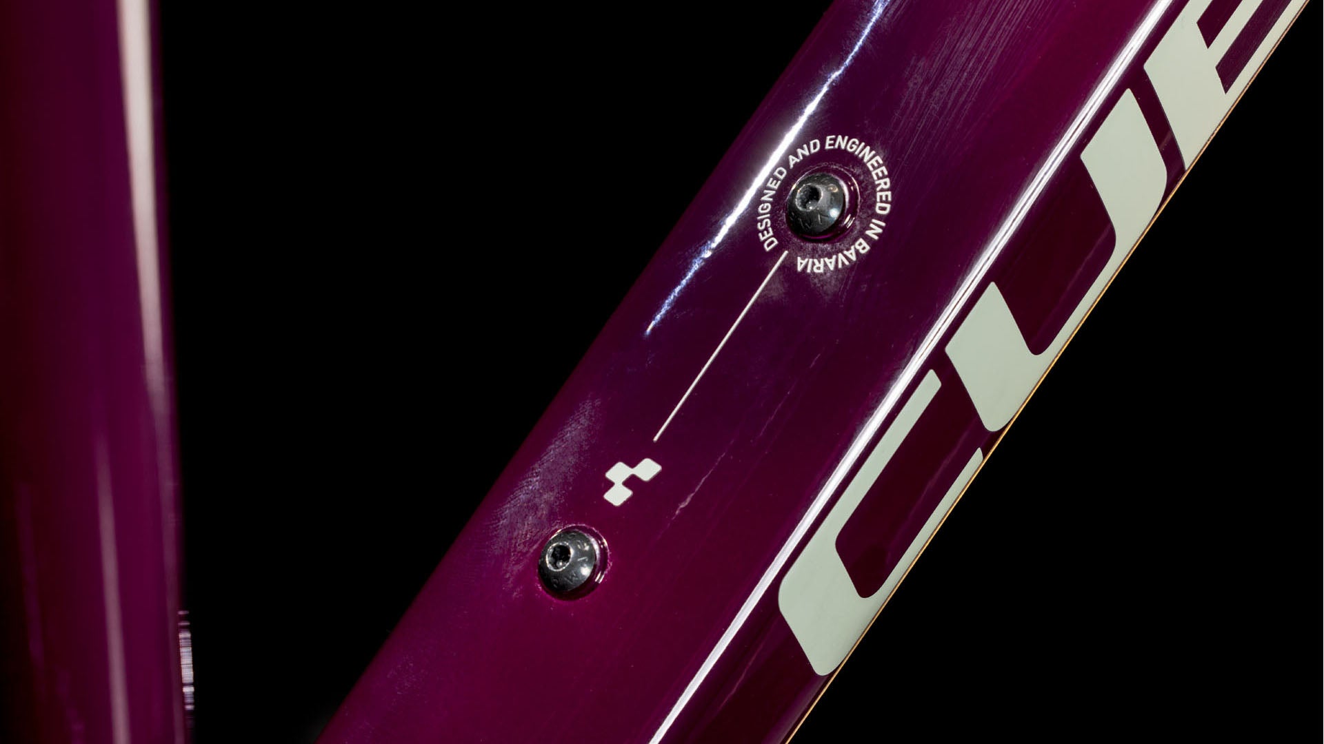 Nahaufnahme eines Cube Nature ONE Allroad amarone'n'lunar Trapeze 2025 Rahmens mit CUBE Branding und "DESIGNED AND ENGINEERED IN GERMANY" Etikett, das eine kleine Pfeilgrafik einkreist. Marke: CUBE.