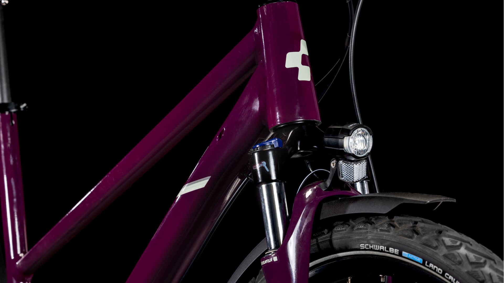 Nahaufnahme der Frontpartie eines CUBE Nature ONE Allroad amarone'n'lunar Trapeze 2025 Trekkingbike mit Federgabel, Scheinwerfer und Schwalbe-Reifen, dargestellt vor schwarzem Hintergrund.