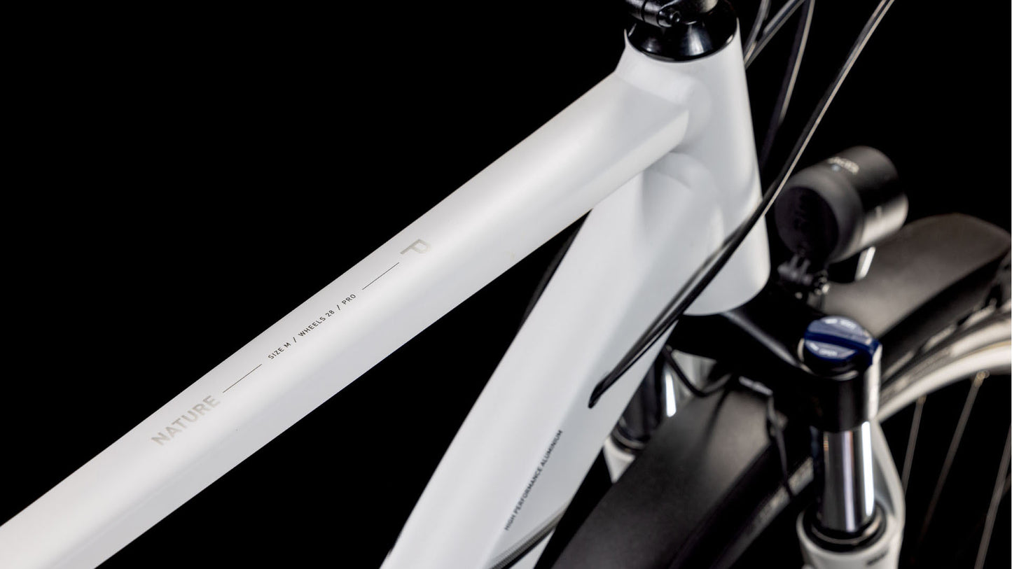 Nahaufnahme des CUBE Nature Pro Allroad cotton'n'grey 2025 mit weißem Aluminiumrahmen mit "NATURE"-Schriftzug auf dem Oberrohr, schwarzem Lenker und Federgabel, vor schwarzem Hintergrund.