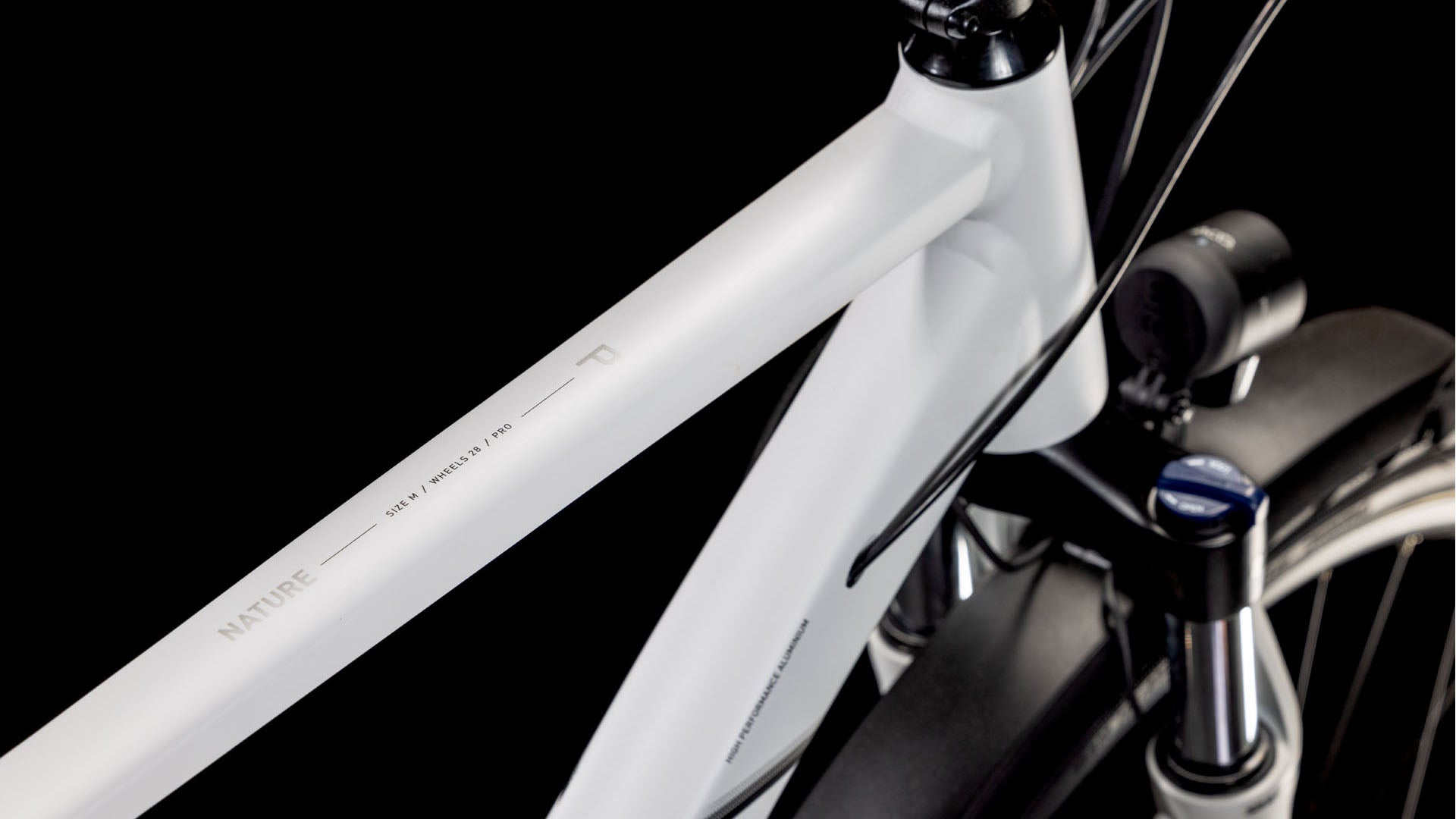 Nahaufnahme des CUBE Nature Pro Allroad cotton'n'grey 2025 mit weißem Aluminiumrahmen mit "NATURE"-Schriftzug auf dem Oberrohr, schwarzem Lenker und Federgabel, vor schwarzem Hintergrund.