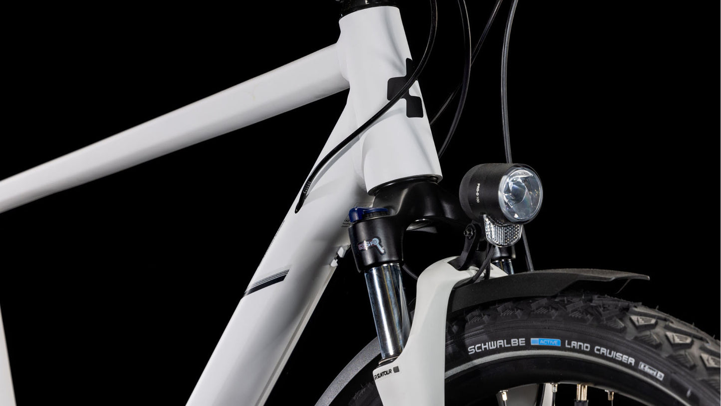 Nahaufnahme der Vorderseite des CUBE Nature Pro Allroad cotton'n'grey 2025, die den Aluminiumrahmen, das Steuerrohr, die vordere Federgabel, den montierten Scheinwerfer und den Schwalbe Land Cruiser-Reifen vor einem schwarzen Hintergrund zeigt.