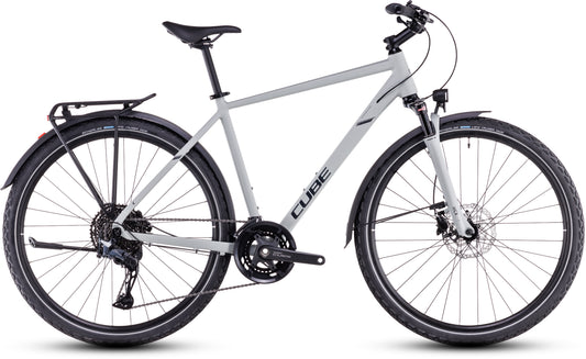 Ein CUBE Cube Nature EXC Allroad Hybrid-Fahrrad in Seasalt'n'Pyrit mit Aluminiumrahmen, Vorderradaufhängung, Shimano Cues-Schaltung, schwarzem Lenker, Gepäckträger und Schutzblechen; dargestellt in der Seitenansicht auf weißem Hintergrund.