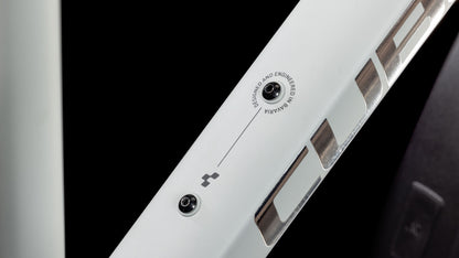 Nahaufnahme des CUBE Nature EXC Allroad seasalt'n'pyrite Trapeze: eine weiße Metalloberfläche mit zwei Schrauben, Lüftungsschlitzen, kleinem Logo und "DESIGNED AND ENGINEERED IN GERMANY" neben einem dünnen Pfeil. Shimano Cues 2x11-Gang inspiriert sein Design. Schwarzer Hintergrund.