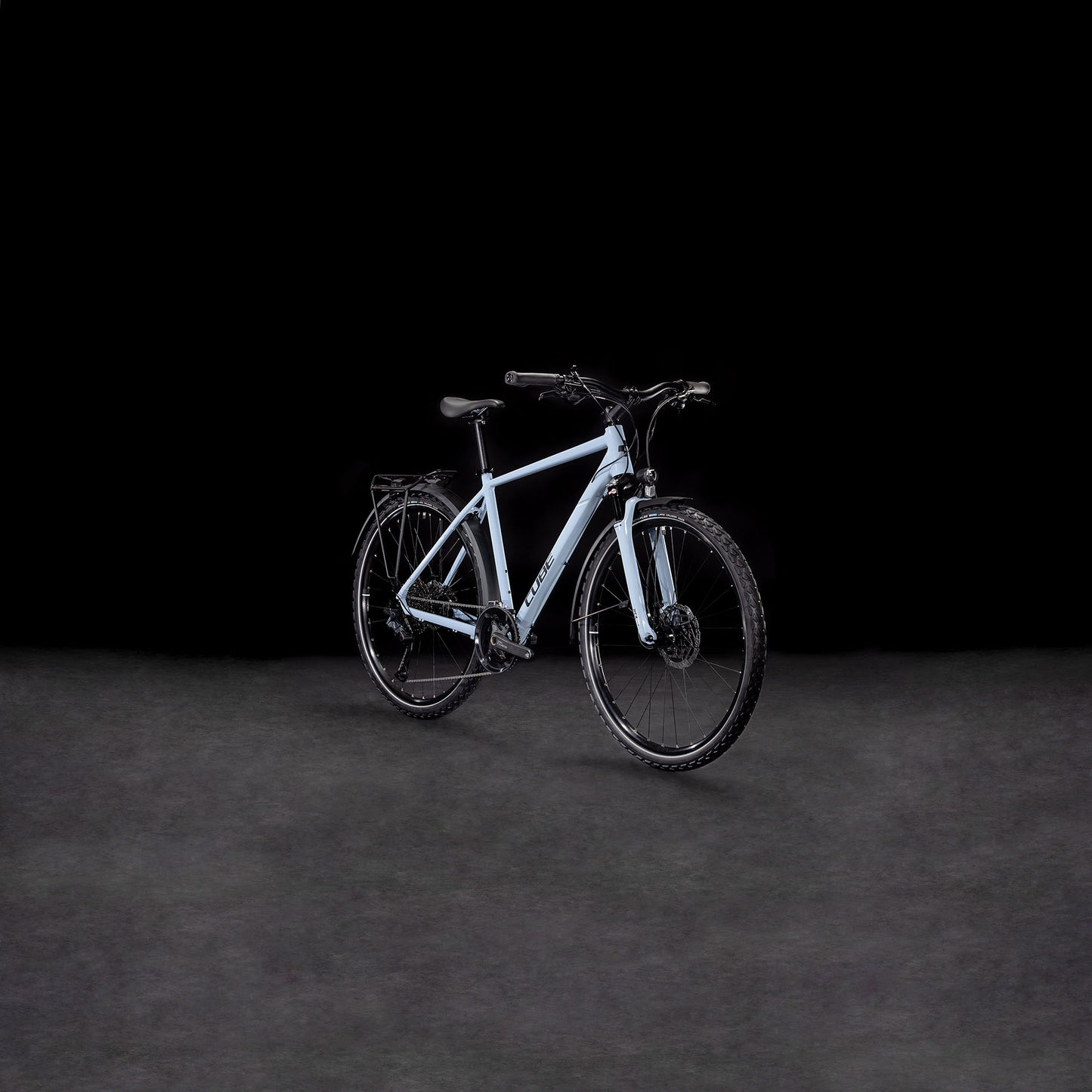 Das CUBE Nature EXC Allroad pigeonblue'n'black Elektrofahrrad mit schwarzen Reifen, Lenker und hydraulischen Scheibenbremsen ist in einem leichten Seitenwinkel auf einem dunklen, neutralen Hintergrund abgebildet.