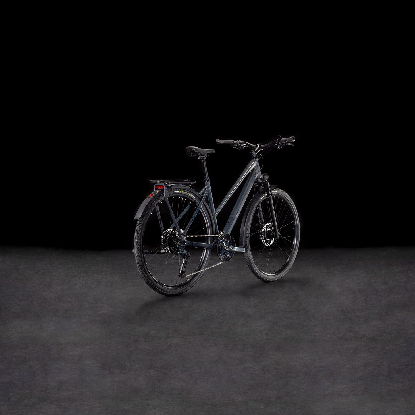 Das CUBE Cube Kathmandu SLX nightsky'n'ink Trapeze 2025, ein modernes E-Bike mit dunklem Rahmen, Schutzblechen, Gepäckträger und Scheibenbremsen - gebaut aus nachhaltigen Materialien - wird vor einem schwarzen Hintergrund aus einem leichten Winkel gezeigt.