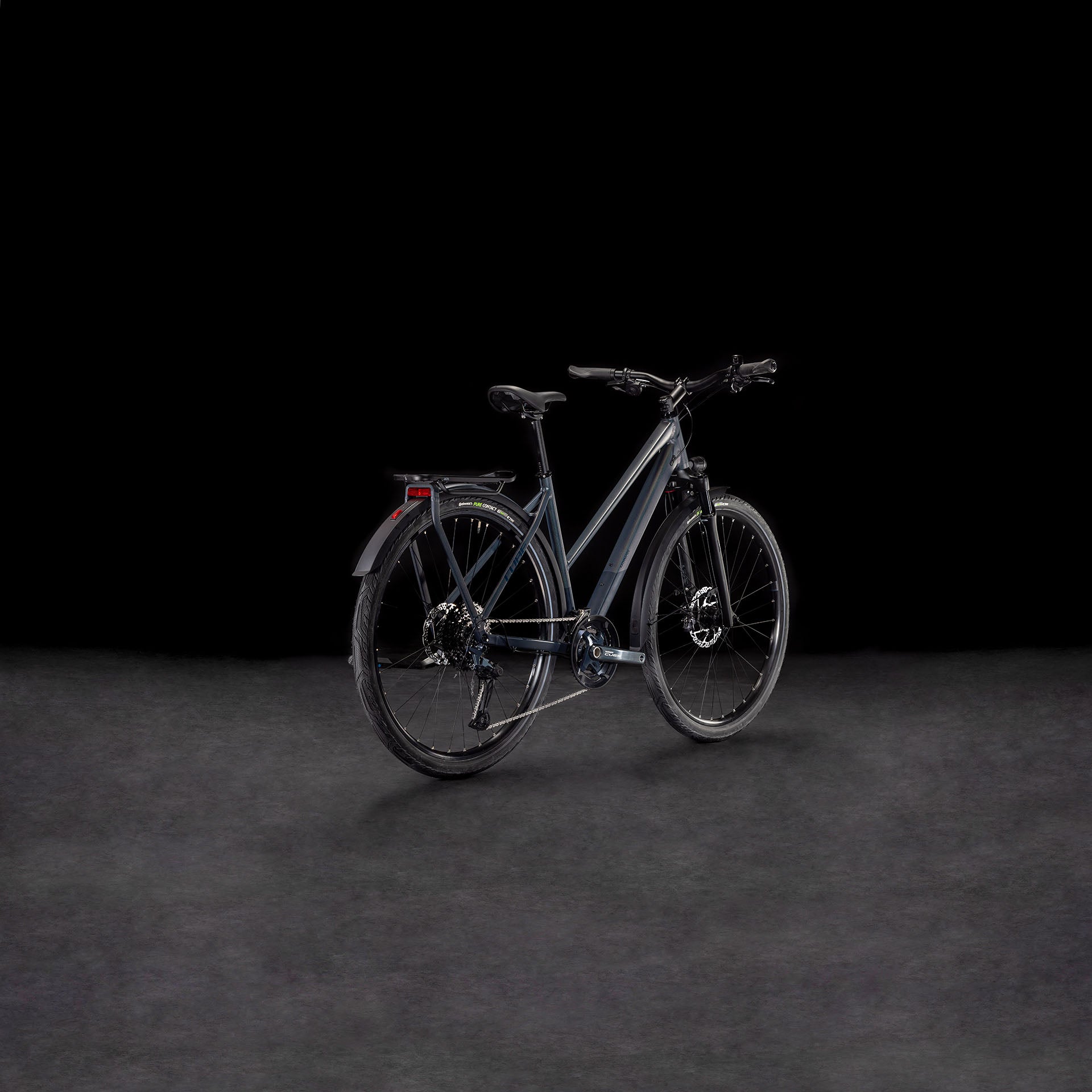 Das CUBE Cube Kathmandu SLX nightsky'n'ink Trapeze 2025, ein modernes E-Bike mit dunklem Rahmen, Schutzblechen, Gepäckträger und Scheibenbremsen - gebaut aus nachhaltigen Materialien - wird vor einem schwarzen Hintergrund aus einem leichten Winkel gezeigt.