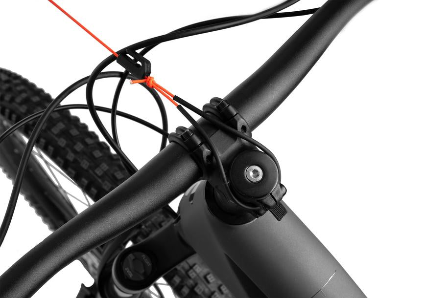Nahaufnahme eines schwarzen Fahrradlenkers und Vorderradreifens mit den ACID Zugsystem MOUNTAIN EXPLORER Kabeln von Cube und einem orangefarbenen Kabelbinder vor einem weißen Hintergrund.