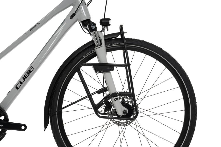 Nahaufnahme des Vorderrads eines weißen Fahrrads mit Scheibenbremse und schwarzem ACID Gepäckträger LOWRIDER Suspension MTB Rack. SCHWALBE steht auf dem Reifen und CUBE auf dem Rahmen - ideal für Fahrten rund um Goslar oder zu Ihrem CUBE Store vor Ort.