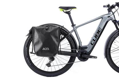 Ein graues CUBE E-Bike mit dem schwarzen ACID Gepäckträger SIC RAIL 29" und einer ACID Gepäcktasche in der Seitenansicht vor weißem Hintergrund - erhältlich in Ihrem CUBE Store in Hildesheim oder Goslar.
