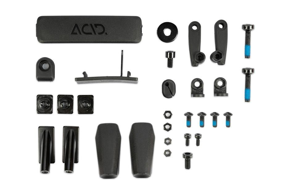 Eine Auswahl an schwarzem Fahrradzubehör und -hardware, darunter Abstandshalter, Schrauben, Muttern, Hebel und Schutzabdeckungen – ideal für Mountainbikes – übersichtlich auf weißem Grund präsentiert. Der größte Artikel ist das ACID Schutzblechset SIC 2.0 84 29" BB Mount von ACID.