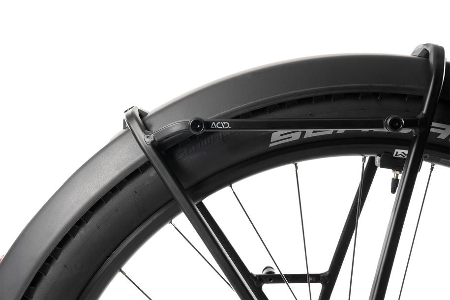 Nahaufnahme eines schwarzen Fahrrad-Hinterrads mit breitem Reifen und einem robusten ACID Gepäckträger SIC 2.0 RAIL von ACID, ideal zur Befestigung von Fahrradtaschen, vor weißem Hintergrund.