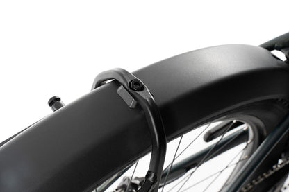 Nahaufnahme eines ACID Gepäckträgers SIC 2.0 RAIL schwarz, montiert auf einem Fahrrad. Zu sehen sind das Hinterradschloss, die Metallspeichen, ein Teil des Rahmens und der Träger für Gepäcktaschen vor einem weißen Hintergrund.