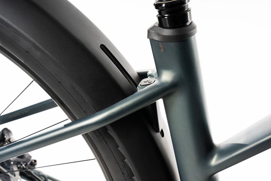 Nahaufnahme eines Fahrradrahmens mit Hinterrad und Sattelrohr in glatter Metallic-Optik, ausgestattet mit dem ACID Gepäckträger SIC 2.0 RAIL schwarz zur Befestigung von Packtaschen an der Rahmen- und Sattelstrebenverbindung.