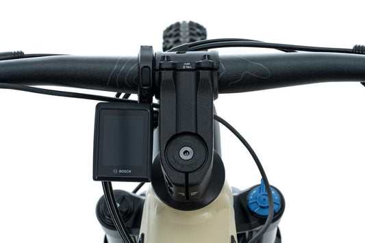 Nahaufnahme eines Fahrradlenkers mit einer Bosch KIOX 300 Anzeige auf der linken Seite, blauen Einstellknöpfen und einer ACID Halterung für Bosch KIOX 300/500 von ACID vor einem weißen Hintergrund.