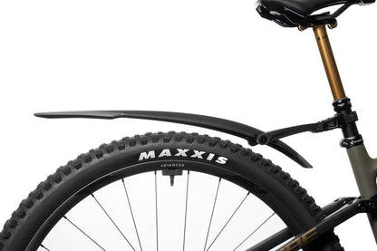 Eine Nahaufnahme des Hinterrads eines Mountainbikes mit einem Maxxis-Reifen und einem ACID Steckschutzblech VANE PRO 27,5-29" RATCHET hinten black'n'grey, aufgenommen vor weißem Hintergrund in einem CUBE Store bei Göttingen.