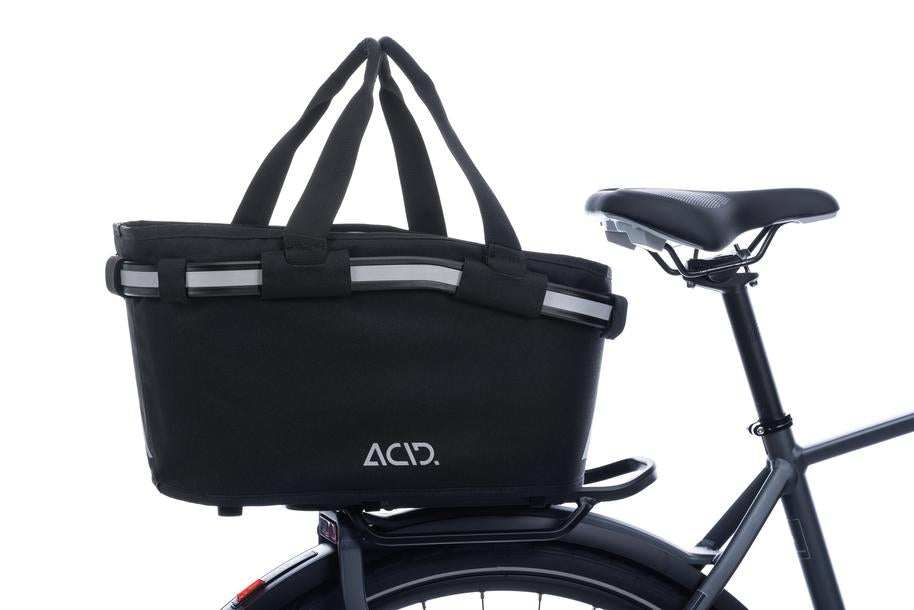 Der ACID Gepäckträgerkorb CITY 20 RILink schwarz von ACID wird am Gepäckträger eines Fahrrads befestigt. Er verfügt über Griffe, reflektierende Elemente, das ACID-Logo an der Seite, einen RILink-Adapter und ist teilweise auf weißem Hintergrund abgebildet.