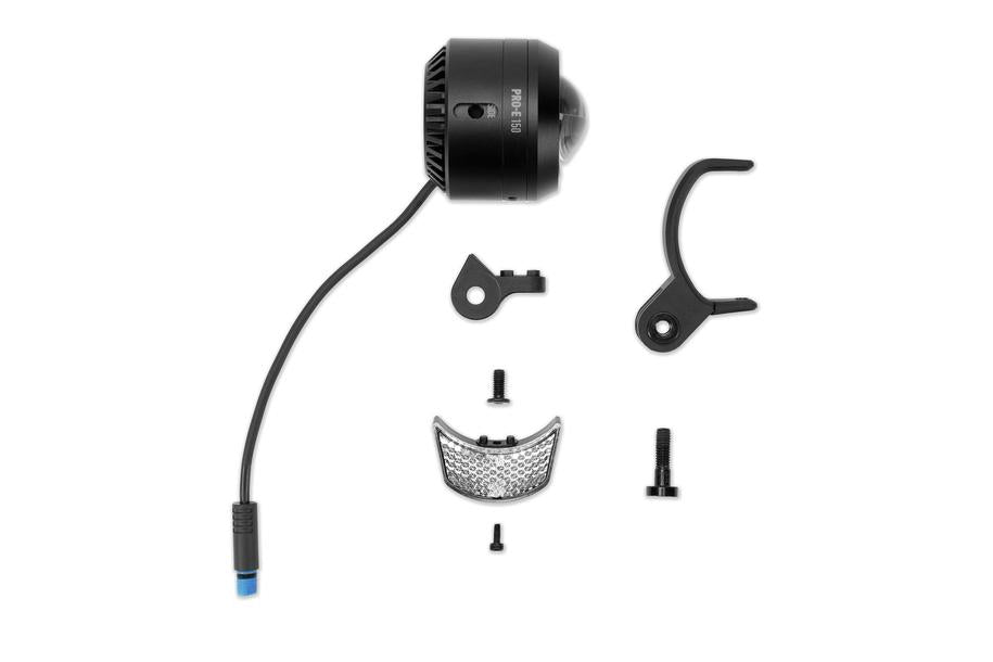 Auf weißem Untergrund ist das ACID E-Bike Frontlicht PRO-E 150 X-Connect von ACID abgebildet, ein schwarzes zylindrisches LED-Fahrradlicht mit fest angeschlossenem Kabel, kleinen schwarzen Halterungen, Reflektorstreifen und Schrauben.
