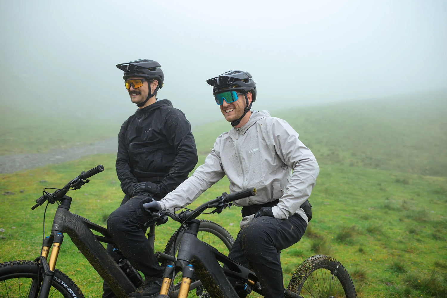 CUBE Stereo Hybrid ONE77 2026 – zwei Mountainbiker im Nebel auf Berghang in den Alpen