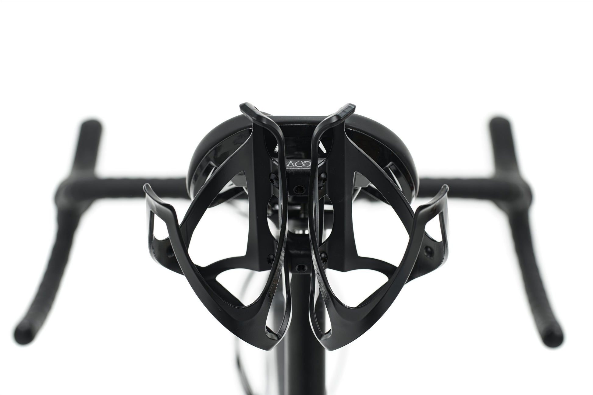 Nahaufnahme eines Fahrradlenkers, eines Vorbaus und zweier schwarzer Flaschenhalter, die hinter dem Sattel mit einem ACID SILink für Flaschenhalter schwarz von ACID montiert sind, dargestellt auf einem Natural Fit Sattel vor weißem Hintergrund.