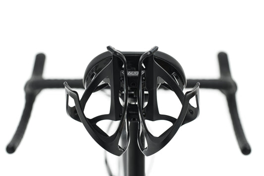 Nahaufnahme eines Fahrradlenkers, eines Vorbaus und zweier schwarzer Flaschenhalter, die hinter dem Sattel mit einem ACID SILink für Flaschenhalter schwarz von ACID montiert sind, dargestellt auf einem Natural Fit Sattel vor weißem Hintergrund.