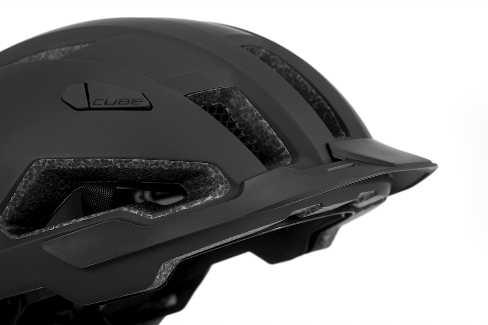 Nahaufnahme des schwarzen Cube Helm EVOY / All Terrain Helm von Cube mit Belüftungsöffnungen, strukturierter Innenpolsterung, aerodynamischer Form, MIPS-System und integriertem Rücklicht vor weißem Hintergrund.