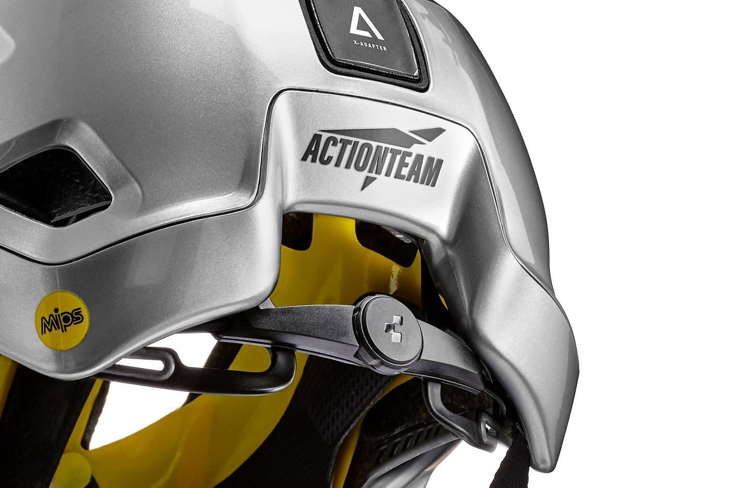 Nahaufnahme eines silbernen CUBE Helm STROVER MTB Enduro Helms mit gelber Innenausstattung, ACTIONTEAM Logo an der Seite, schwarzem Cube Natural Fit System Einstellrad und sichtbarem MIPS Technologie Sicherheitsaufkleber.